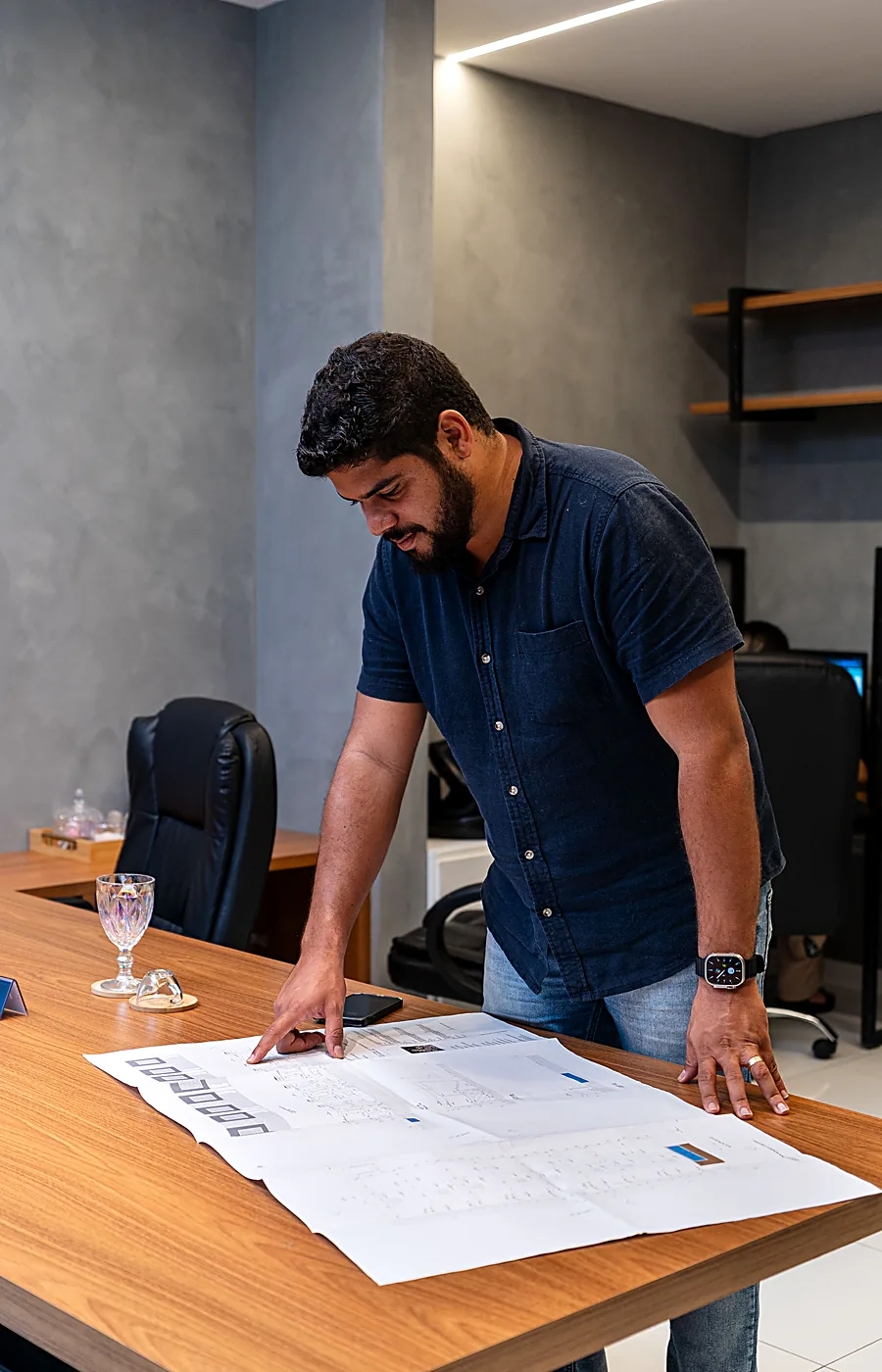Marco Machado, à frente da MM Construtora, conferindo a planta de uma obra no escritório